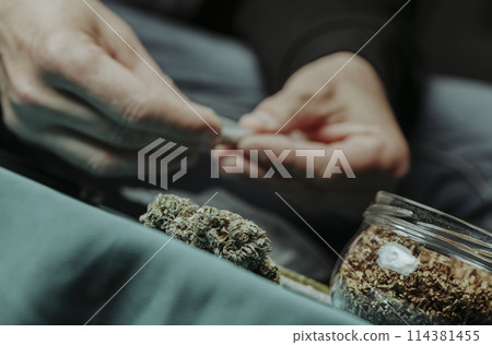 man rolling a joint, sitting at a table man rolling a joint, sitting at a table 114381455