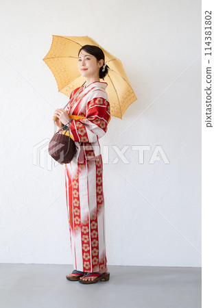穿著浴衣的可愛日本女人拿著日本和服來抵禦夏日的陽光。 114381802