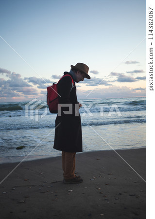 Serenity at dusk man walks along tranquil seashore. Serenity at dusk man walks along tranquil seashore. 114382067