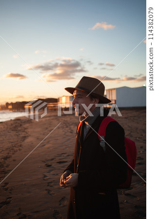 Peaceful beach scene with man walking at sunset. 114382079
