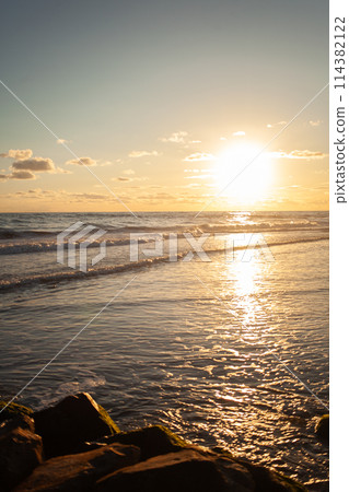 Coastal horizon aglow in warm hues as sun sets. Coastal horizon aglow in warm hues as sun sets. 114382122