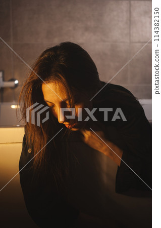 Lonely woman sitting slumped in bathtub, fully clothed. Lonely woman sitting slumped in bathtub, fully clothed. 114382150