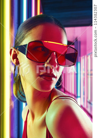 Close up portrait of young, beautiful woman with bright, modern accessories posing in neon light against striped illuminated background. 114382307