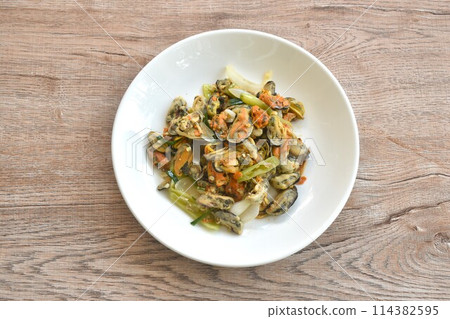 spicy stir fried mussel with slice onion and chili couple egg on plate  114382595