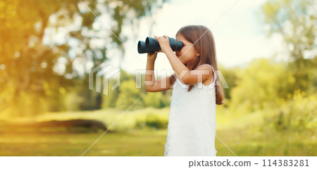 Little girl child looking through binoculars outdoors on summer day 114383281