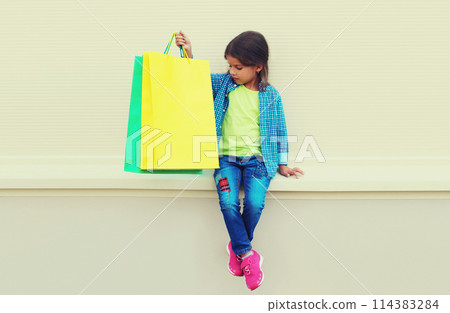 Little girl child with shopping bags posing on city street 114383284