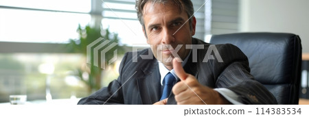 European businessman showing thumbs up in his office, success and achievement concept, banner 114383534