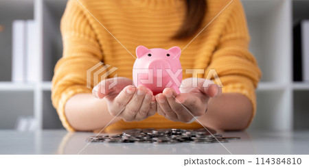 A woman is holding a piggy bank in his hands for a money or finance concept, support saving bank, Protect saving money concept A woman is holding a piggy bank in his hands for a money or finance concept, support saving bank, Protect saving money concept 114384810