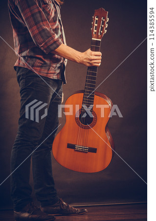 Man is standing with guitar. 114385594