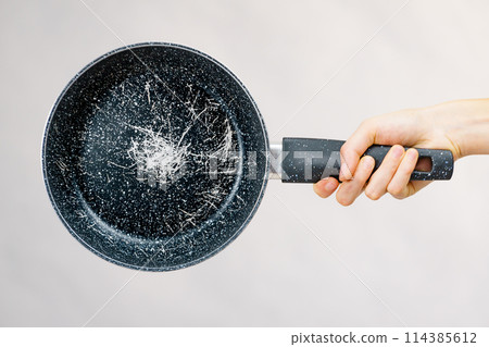 Hand holding scratched frying pan 114385612