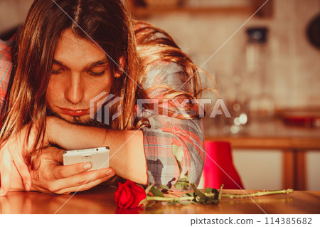 Worried man with rose and mobile phone. Worried man with rose and mobile phone. 114385682