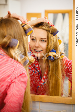 Woman curling her hair using rollers Woman curling her hair using rollers 114385835