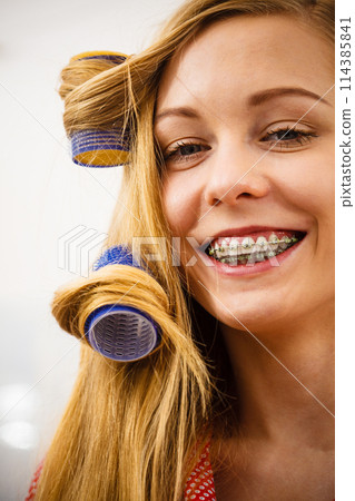 Woman curling her hair using rollers Woman curling her hair using rollers 114385841