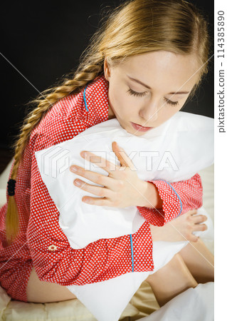Sad depressed girl in bed gripping pillow 114385890