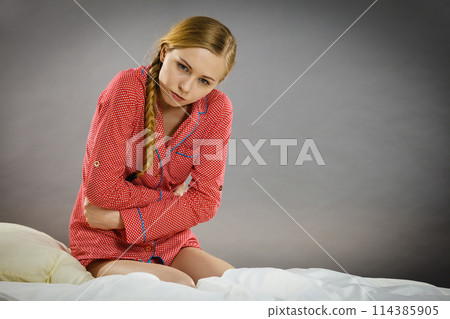 Sad young teenager woman on bed feeling pain Sad young teenager woman on bed feeling pain 114385905