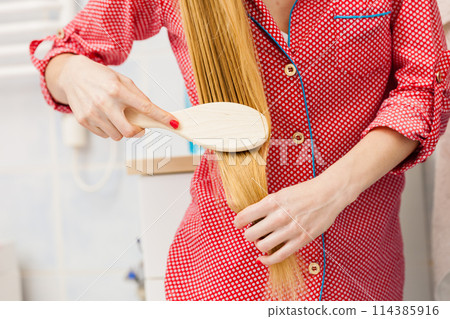 Woman brushing her long hair in bathroom 114385916