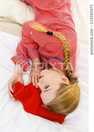 Woman sleeping with warm red hot water bottle Woman sleeping with warm red hot water bottle 114385975