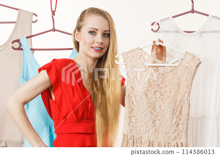 Woman in shop or wardrobe picking dress Woman in shop or wardrobe picking dress 114386013