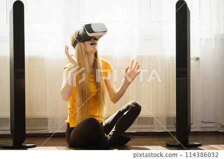 Girl wearing virtual reality goggles at home 114386032
