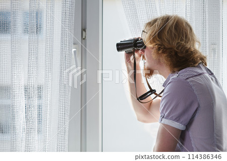 Man with binoculars spying on neighbors Man with binoculars spying on neighbors 114386346