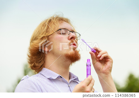 Man blowing soap bubbles, having fun Man blowing soap bubbles, having fun 114386365