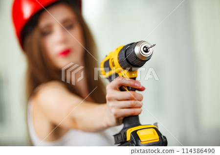 Woman using power driil for work at home 114386490