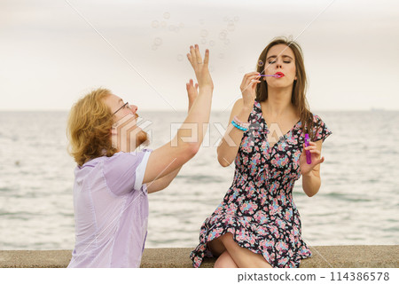Couple playing with soap bubbles 114386578