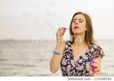 Woman blowing bubbles outdoor 114386580