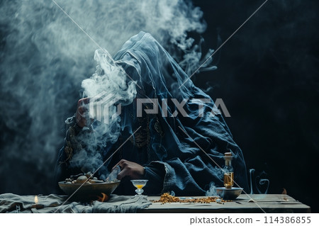The medieval alchemist make magic ritual at the table in his smoke laboratory. 114386855