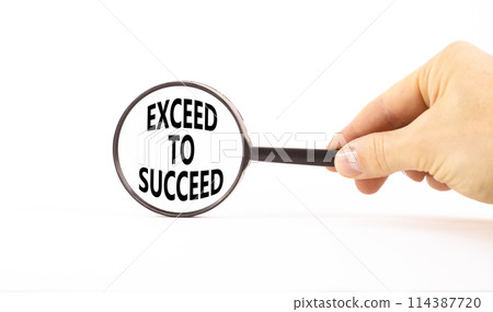 Exceed to succeed symbol. Concept words Exceed to succeed in beautiful magnifying glass. Beautiful white table white background. Businessman hand. Business and exceed to succeed concept. Copy space. 114387720