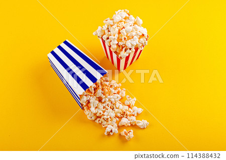 Glass with popcorn on a yellow background 114388432