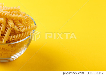 Different types and shapes of dry italian pasta on a yellow background Different types and shapes of dry italian pasta on a yellow background 114388447