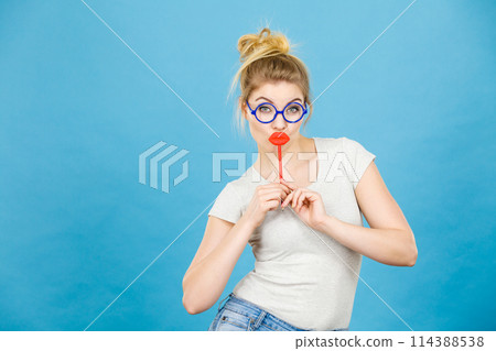 Happy woman holding fake lips on stick Happy woman holding fake lips on stick 114388538