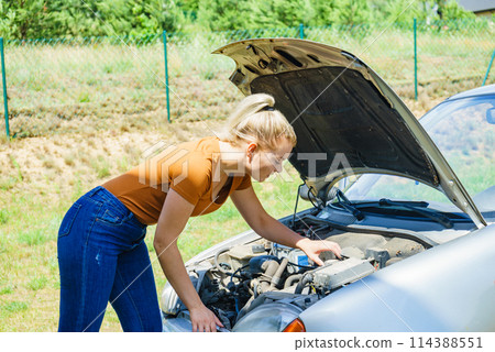Woman standing near broken down car 114388551