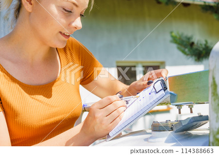 Woman checking level of propane gas in tank Woman checking level of propane gas in tank 114388663