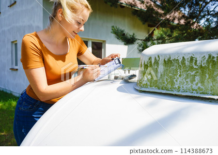 Woman checking level of propane gas in tank Woman checking level of propane gas in tank 114388673