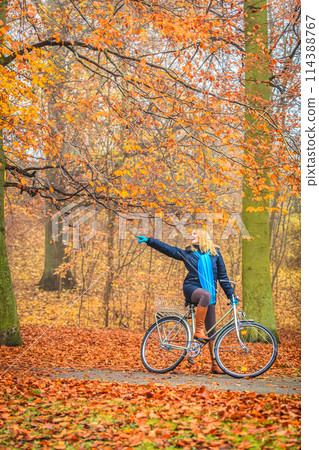 Active woman riding bike in autumn park. 114388767