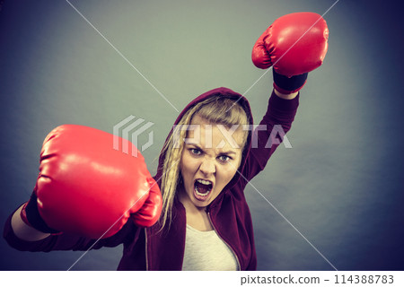 Angry woman wearing boxing gloves Angry woman wearing boxing gloves 114388783