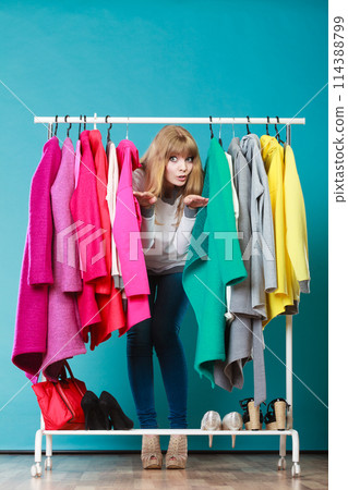 Woman sneaking among clothes in mall or wardrobe. Woman sneaking among clothes in mall or wardrobe. 114388799