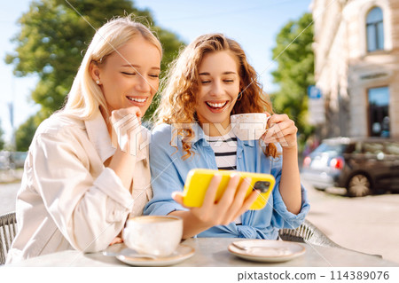 Two young women sitting in the cafe. Coffee break after shopping. Blogging, tourism. Two young women sitting in the cafe. Coffee break after shopping. Blogging, tourism. 114389076