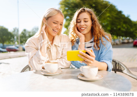 Two young women sitting in the cafe. Coffee break after shopping. Blogging, tourism. Two young women sitting in the cafe. Coffee break after shopping. Blogging, tourism. 114389078