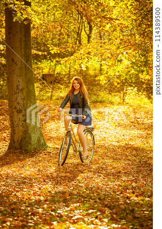 Redhead lady cycling in park. 114389500