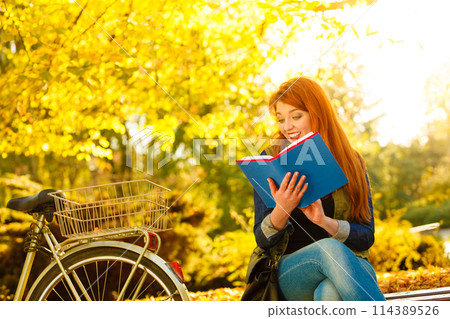 woman girl relaxing in autumnal park reading book woman girl relaxing in autumnal park reading book 114389526