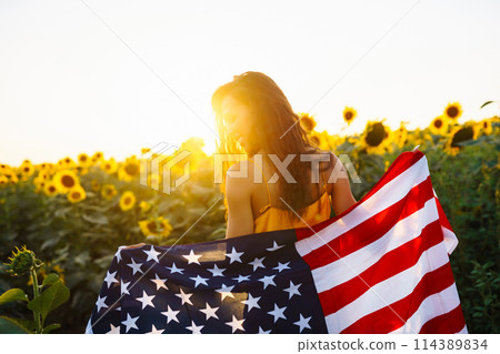 Woman proudly hold waving american USA flag in in the sunflower field. Independence Day, 4th July. Woman proudly hold waving american USA flag in in the sunflower field. Independence Day, 4th July. 114389834