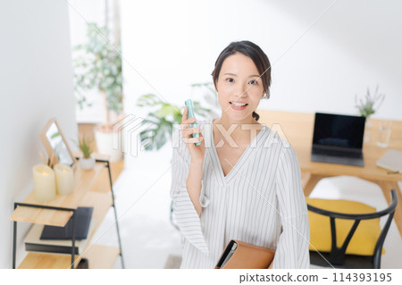 A woman in her 30s making a phone call on her smartphone A woman in her 30s making a phone call on her smartphone 114393195