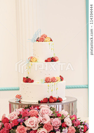 A cute three-tiered cake topped with strawberries 114394444