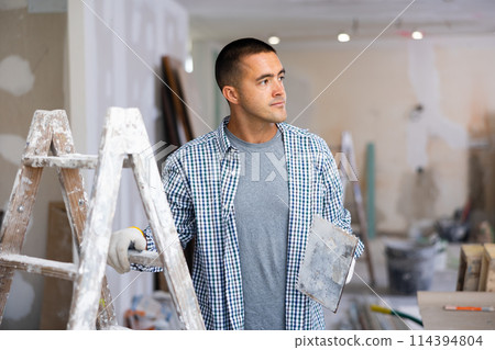 Portrait of man with float trowel in building site Portrait of man with float trowel in building site 114394804
