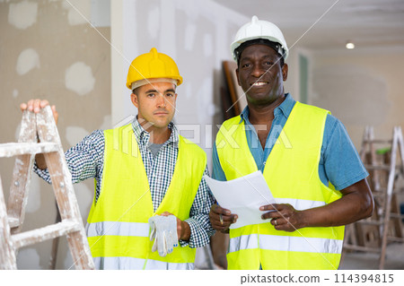 Portrait of positive men builders inside apartment during repair works Portrait of positive men builders inside apartment during repair works 114394815