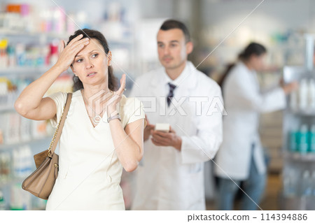 Male pharmacist advises medicine for headache to woman Male pharmacist advises medicine for headache to woman 114394886