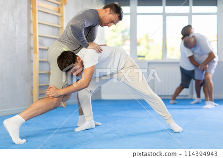 Judo lessons - young guy makes power throw during judo or sambo classes 114394943